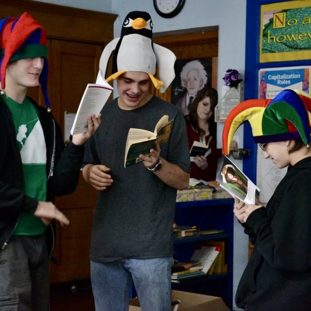 Students wearing colorful hats and reading from books