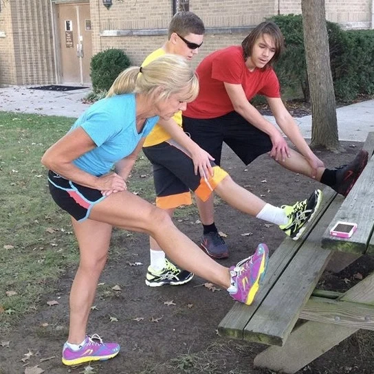 A group stretching their legs on a picnic bench outdoors
