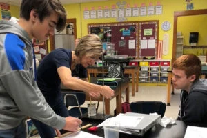 A group working with equipment over a tray on a classroom table
