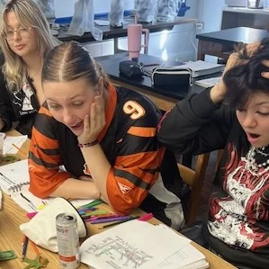 Students at a table with drawings and colored pencils