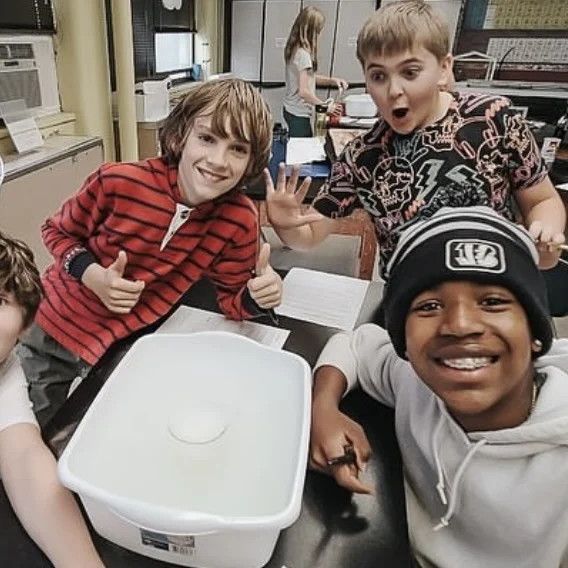 Students gathered around a plastic tub on a classroom table