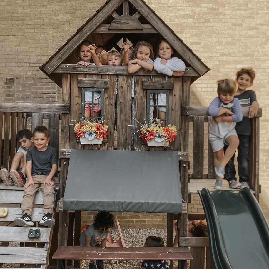 Children playing on a wooden play structure with a slide