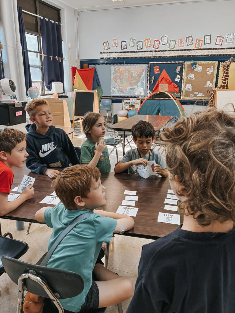 Children gathered around a table with books and word cards