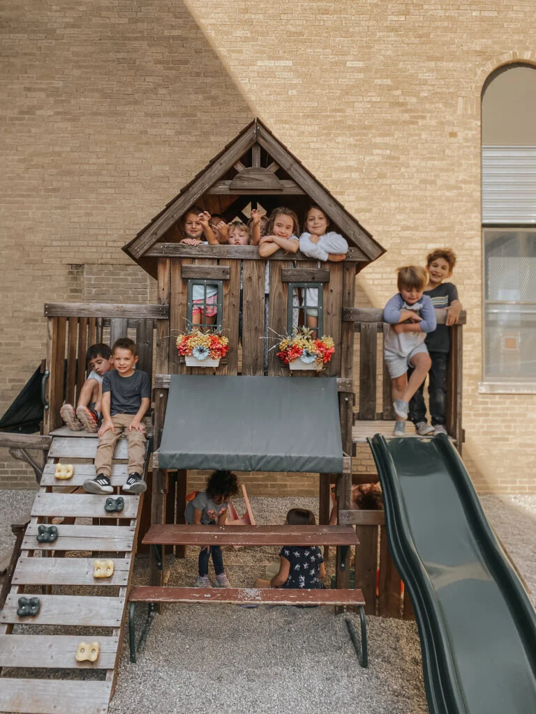Children playing on a wooden play structure with a slide