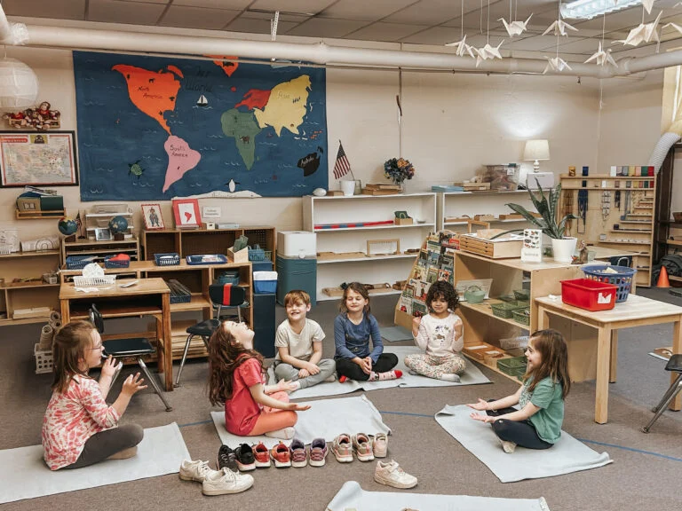 Children sitting in a circle on classroom floor mats